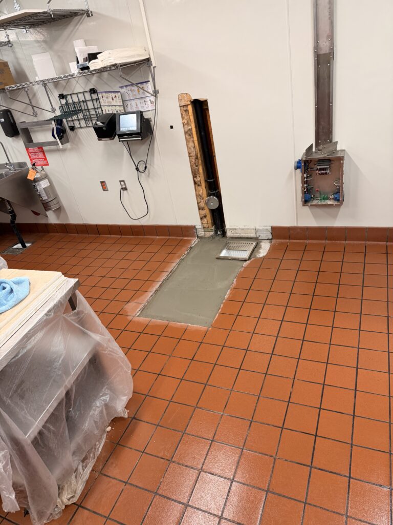 Completed floor sink installation and cleaned work area in a commercial restaurant